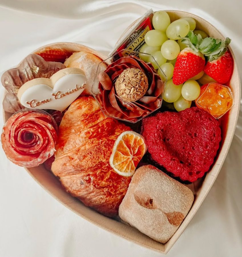 Cesta em formato de coração com croissant, frutas, doces e biscoito “Com carinho”