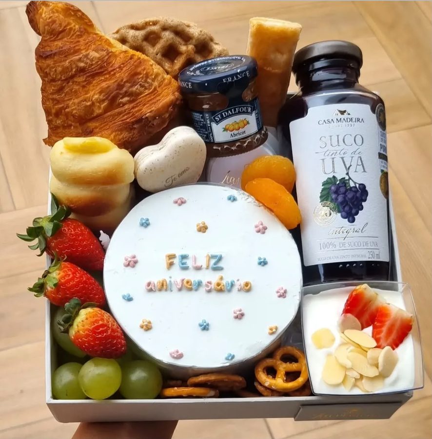 Caixa de café da manhã com mini bolo “Feliz aniversário”, croissant, frutas e suco
